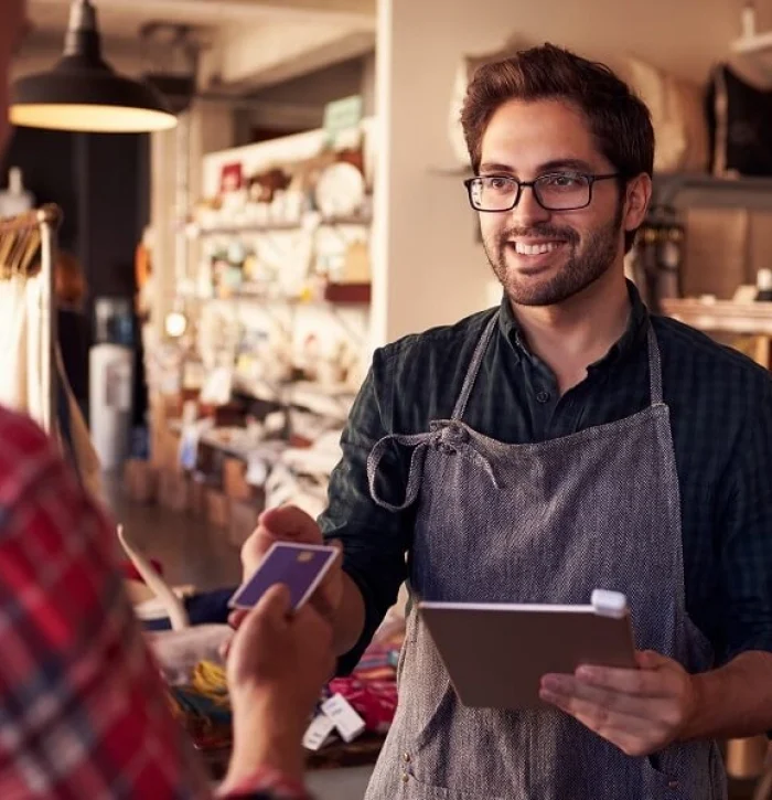 Man working in retail takes card from customer for payment.